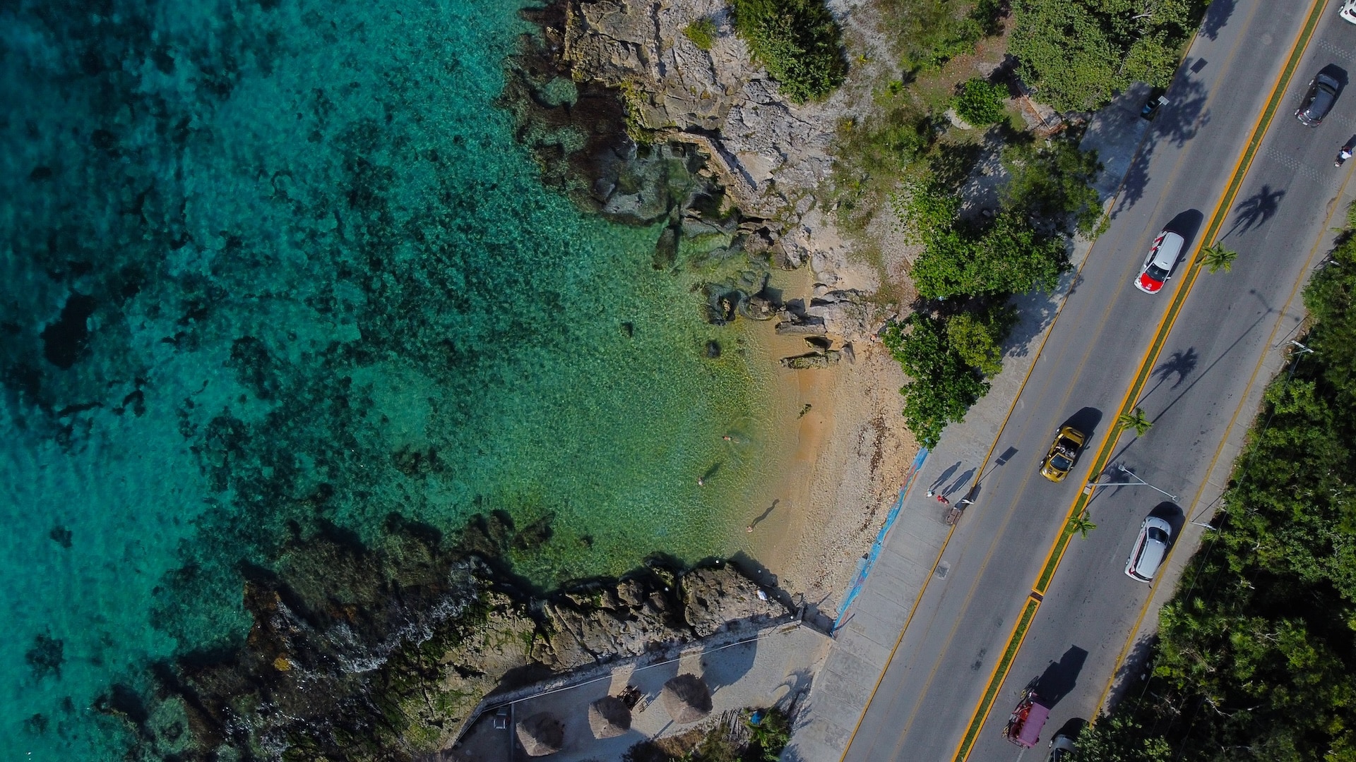 Turquoise Caribbean water beside a quiet coastal road in Cozumel — an accessible, internationally known island setting